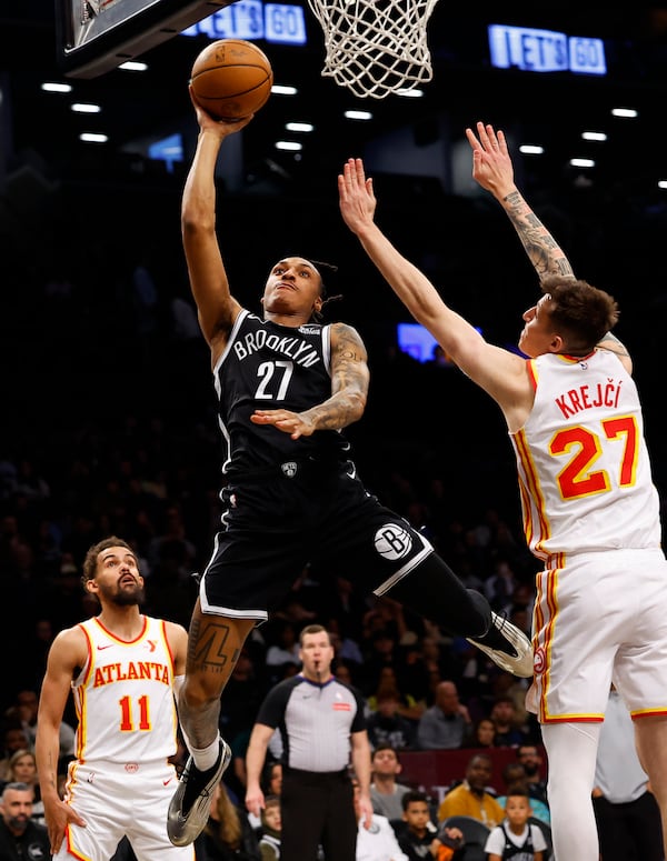 Brooklyn Nets forward Maxwell Lewis (27) shoots over Atlanta Hawks guards Vit Krejci (27) and Trae Young (11) during the first half of an NBA basketball game, Sunday, March 16, 2025, in New York. (AP Photo/Noah K. Murray)