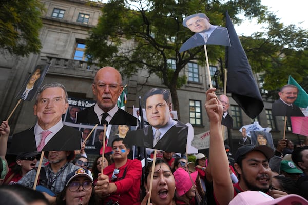 FILE - Justice employees hold up cutouts of Supreme Court justices in a show of support as they discuss a draft ruling that proposes the partial invalidation of the judicial reform approved by Congress, in Mexico City, Nov. 5, 2024. (AP Photo/Fernando Llano, File)