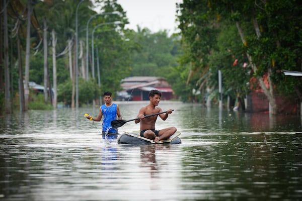 Children wade through flood waters in Tumpat, outskirts of Kota Bahru, Malaysia, Tuesday, Dec. 3, 2024. (AP Photo/Vincent Thian)