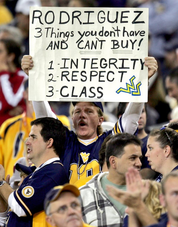 FILE - A West Virginia fan holds a sign referencing former head coach Rich Rodriguez during the first half of the Fiesta Bowl college football game against Oklahoma, Wednesday, Jan. 2, 2008 in Glendale, Ariz. (AP Photo/Matt York, File)