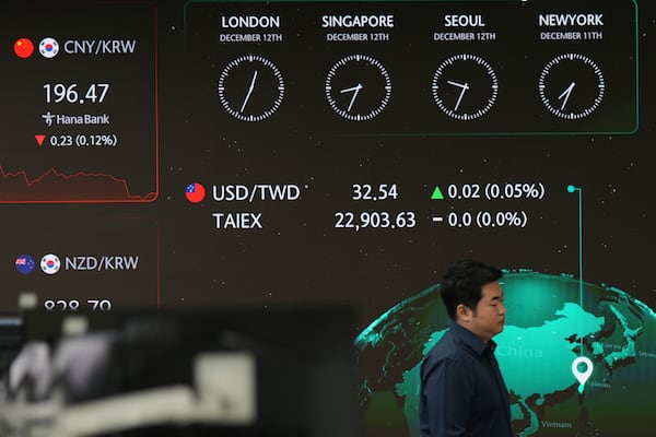 A currency trader walks near the screens showing the foreign exchange rates at a foreign exchange dealing room in Seoul, South Korea, Thursday, Dec. 12, 2024. (AP Photo/Lee Jin-man)