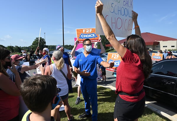 Dr. Jaha Howard (center), a Cobb County School board member, is surrounded by protesters during a rally to call on Superintendent Chris Ragsdale and the Cobb school board to offer in-person classes alongside virtual learning. The protest was held outside Cobb County Civic Center in Marietta on Saturday, August 1, 2020. (Photo: Hyosub Shin / Hyosub.Shin@ajc.com)