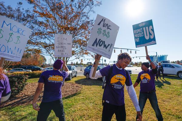 Airport workers wave signs as they strike in front of the Charlotte Douglas International Airport in Charlotte, N.C., Monday, Nov. 25, 2024. (AP Photo/Nell Redmond)