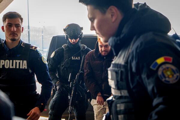 Mohamed Amra, nicknamed ''The Fly", is escorted by armed police officers at the Henri Coanda international airport in Otopeni, Romania, Tuesday, Feb. 25, 2025, before being extradited to France. (AP Photo/Vadim Ghirda)