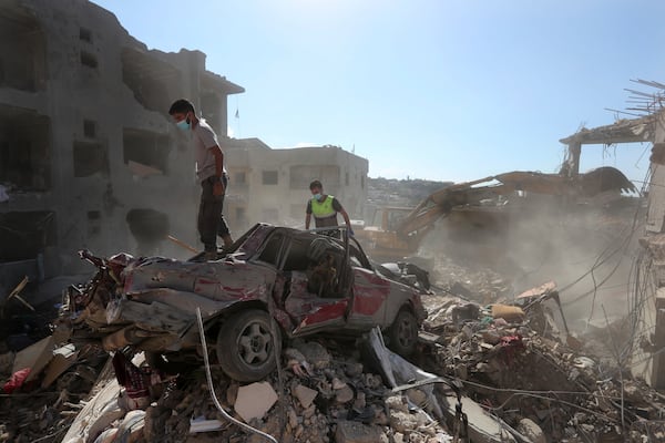 Rescue worker stand on a destroyed car over the rubble of a destroyed building hit by an Israeli airstrike in Saksakiyeh village, south Lebanon, Tuesday, Nov. 12, 2024. (AP Photo/Mohammed Zaatari)