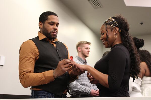 Damien Jenkins places a Ring Pop on Tiffany Jenkins' finger as the two exchange vows during the Valentine's Day group wedding in Cobb County Magistrate Court on Friday, Feb. 14, 2025. (Taylor Croft/Taylor.Croft@ajc.com)