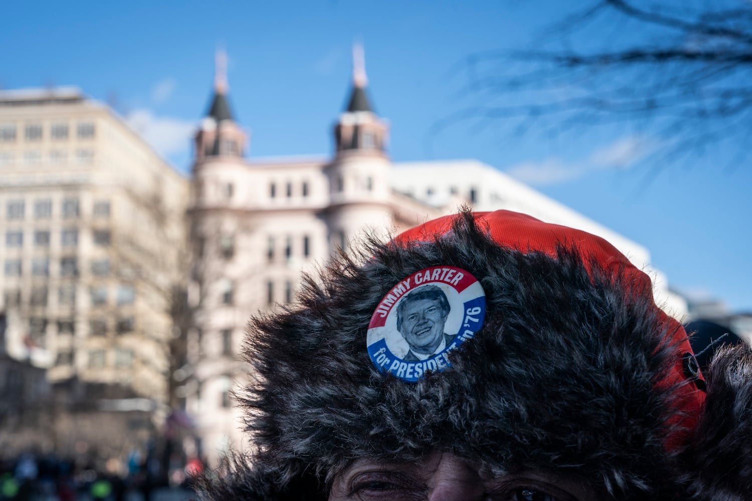 A mourner wears a campaign pin for President Jimmy Carter as his coffin arrives at the U.S. Navy Memorial in Washington, on Tuesday, Jan. 7, 2025, before traveling on to the Capitol where Carter will lie in state. (Haiyun Jiang/The New York Times)