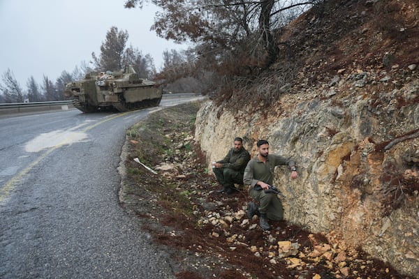 Israeli soldiers take cover on the side of the road during an alert of incoming rockets, near Kiryat Shmona, northern Israel Sunday Nov. 24, 2024. (AP Photo/Ohad Zwigenberg)