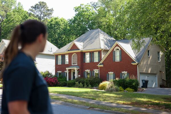 Neighbor Jillian Scelsi looks at the Powder Springs home where a man illegally squatted before being arrested last week. (Jason Getz / AJC)
