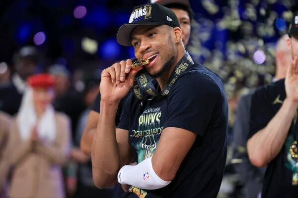 Milwaukee Bucks forward Giannis Antetokounmpo (34) bites his NBA Cup medal after his team's victory in the championship game of the NBA Cup basketball tournament against the Oklahoma City Thunder Tuesday, Dec. 17, 2024, in Las Vegas. (AP Photo/Ian Maule)