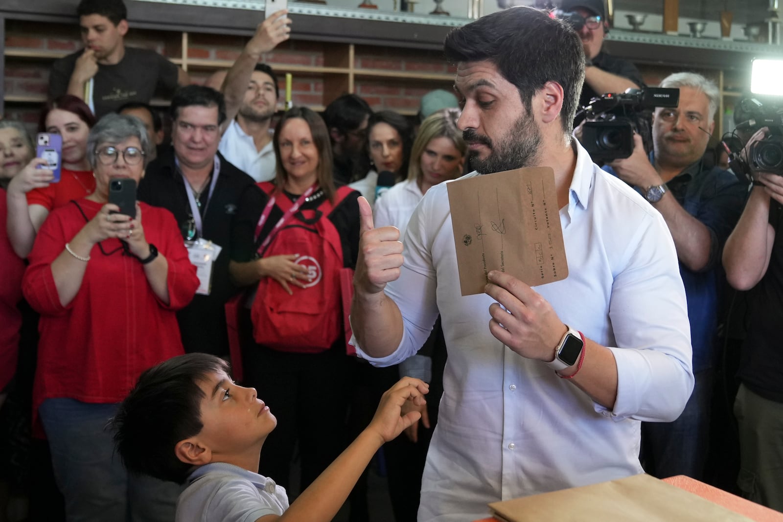 Andres Ojeda, Colorado Party presidential candidate, holds up his ballot at a polling station during general elections in Montevideo, Uruguay, Sunday, Oct. 27, 2024. (AP Photo/Matilde Campodonico)