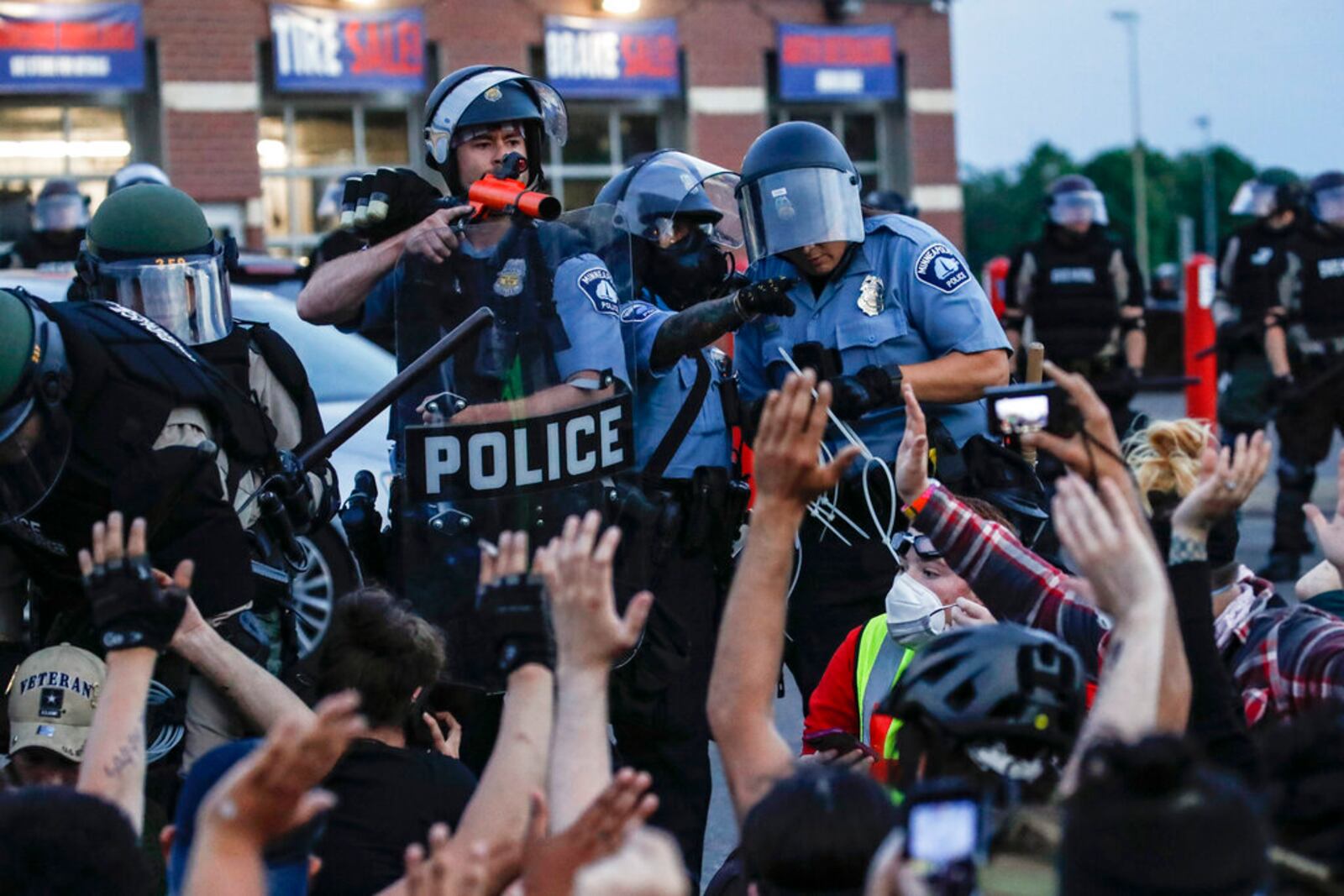 FILE - In this Sunday, May 31, 2020, file photo, a police officer points a hand cannon at protesters who have been detained pending arrest on South Washington Street, in Minneapolis. President Donald Trump has characterized those clashing with law enforcement in the wake of George Floydâs death under the knee of a Minneapolis police officer as radical-left thugs engaging in domestic terrorism. The Associated Press has found that more than 85 percent of those charged by police were locals. Only a handful appeared to have any affiliation with organized groups involved in the protests. (AP Photo/John Minchillo, File)