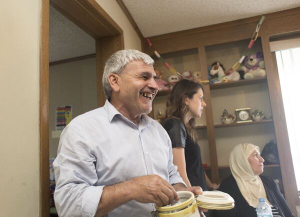 Taha Youssef, left, laughs at a story told during dinner at his home in Decatur. Chad Rhym / Chad.Rhym@ajc.com