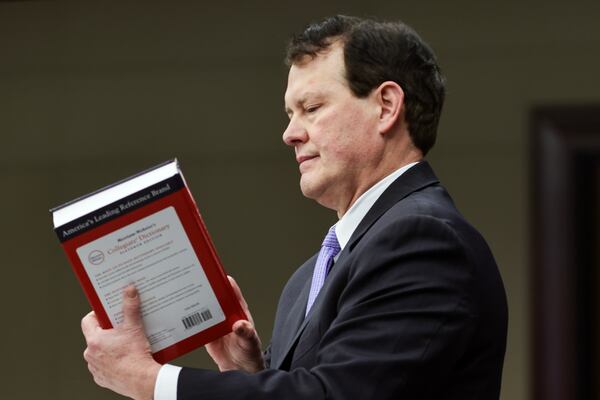 Plaintiff attorney Ray Smith III holds up a dictionary as he makes opening remarks during a lawsuit hearing in the Cobb Board of Commissioners redistricting case at Cobb County Superior Court on Monday, Nov. 20, 2023. (Natrice Miller/ Natrice.miller@ajc.com)