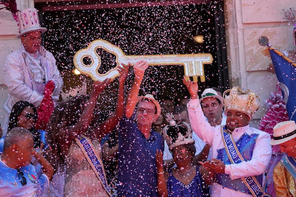 Carnival King Momo, Kaio Mackenzie, right, with Queen Thuane de Oliveira, hold up the keys of the city from Mayor Eduardo Paes, center, at a ceremony officially kicking off Carnival in Rio de Janeiro, Brazil, Friday, Feb. 28, 2025. (AP Photo/Silvia Izquierdo)