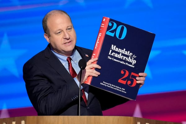 FILE - Colorado Gov. Jared Polis holds up a copy of Project 2025 as he speaks during the Democratic National Convention Aug. 21, 2024, in Chicago. (AP Photo/J. Scott Applewhite, File)