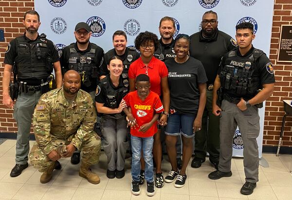 Fairburn officers pose with the children of Sgt. Jean-Harold Astree before the first day of school Wednesday in Douglas County.