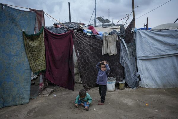 Palestinian children play on the dirt next to the tents of a camp for displaced people in Deir al-Balah, Gaza Strip, on Thursday, Dec. 12, 2024. (AP Photo/Abdel Kareem Hana)