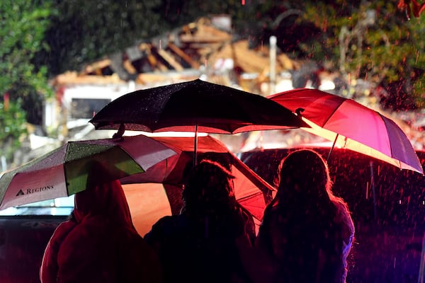 Bystanders watch as first responders work to free a victim after a tree fell on a house in Natchez, Miss., Saturday, Dec. 28, 2024. (Thomas Graning/The Natchez Democrat via AP)