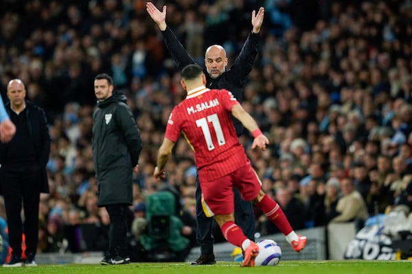 Manchester City's head coach Pep Guardiola, back, gestures as Liverpool's Mohamed Salah reaches the ball during the English Premier League soccer match between Manchester City and Liverpool at Etihad stadium in Manchester, England, Sunday, Feb. 23, 2025. (AP Photo/Dave Thompson)