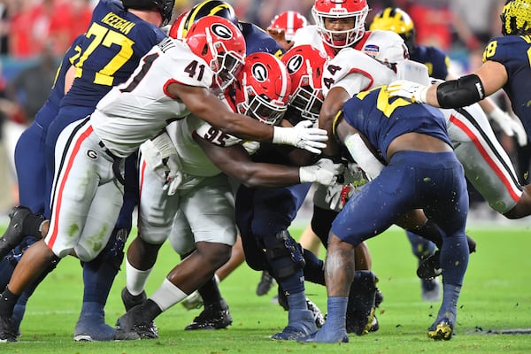 Members of the Georgia Bulldogs defense tackle Michigan Wolverines running back Hassan Haskins (25). (Hyosub Shin / Hyosub.Shin@ajc.com)