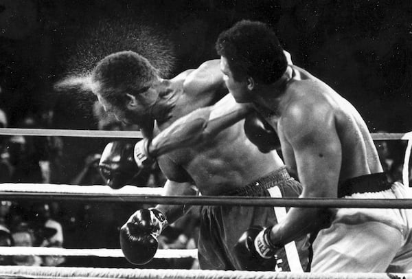 FILE - Perspiration flies from the head of George Foreman as he takes a right from challenger Muhammad Ali in the seventh round in the match dubbed Rumble in the Jungle in Kinshasa, Zaire, Oct. 30, 1974. (AP Photo/Ed Kolenovsky, File)