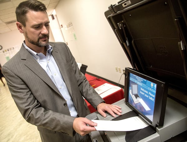 Jeb Cameron with Election Systems & Software demonstrates  paper-ballot voting machines at the Rockdale County Board of Elections in Conyers on Sept. 5, 2017. STEVE SCHAEFER / SPECIAL TO THE AJC