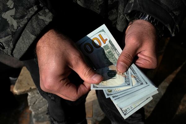 A man poses for a photo without showing his face as he counts U.S. dollars at Ferdowsi street, Tehran's go-to venue for foreign currency exchange, in downtown Tehran, Iran, Wednesday, Dec. 18, 2024. (AP Photo/Vahid Salemi)