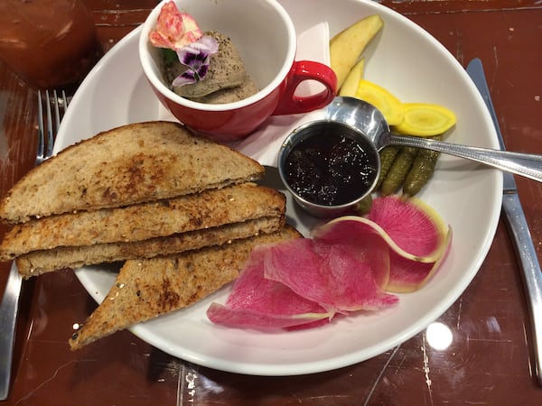 The chicken liver mousse at Petit Chou comes with toast, jam, cornichons, and fresh apple, yellow carrot and watermelon radish slices. CONTRIBUTED BY WENDELL BROCK