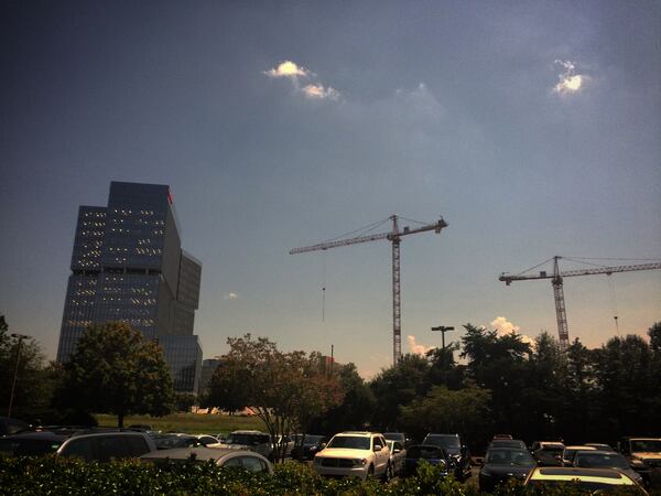 Two tower cranes stand motionless at the State Farm construction site near Perimeter Mall in Dunwoody during the solar eclipse on Monday, August 21, 2017. J. SCOTT TRUBEY/STRUBEY@AJC.COM