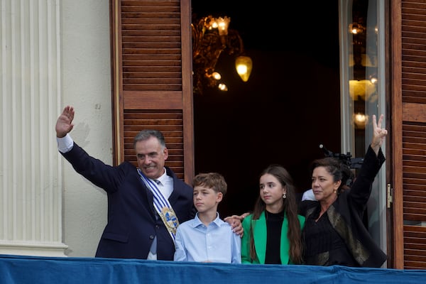 Uruguay's newly sworn-in President Yamandu Orsi and first lady Laura Alonso Perez wave from an Estevez Palace balcony, accompanied by their children, Victorio and Lucia, on Inauguration Day in Montevideo, Uruguay, Saturday, March 1, 2025. (AP Photo/Matilde Campodonico)