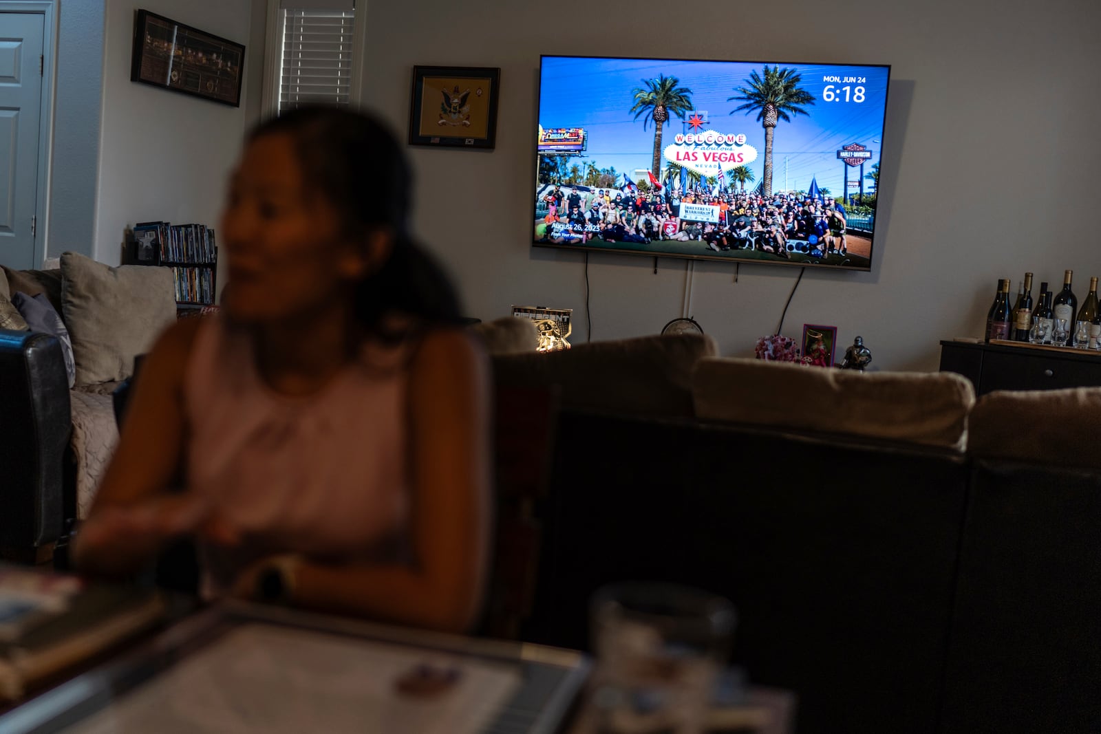 An image of a veterans support gathering Leah Elmquist attended is displayed on the television as she sits in her home, Monday, June 24, 2024, in Las Vegas. "That's why I joined the military. I felt so lucky to be an American, ironically. I wanted to thank this country for raising me," she said. "I didn't think about citizenship because I felt I was being more American than most Americans." (AP Photo/David Goldman)