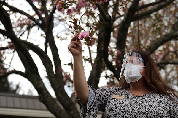 Administrator Jennifer Vasil looks at a blooming cherry blossom tree that will be part of a memorial for residents and staff member who died of COVID-19. Vasil is ordering a granite bench to be placed there. “Curtis Compton / Curtis.Compton@ajc.com”