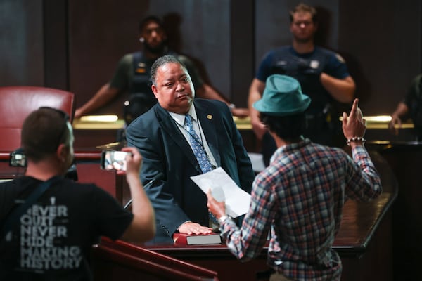 Council member Michael Julian Bond puts his hand on a bible as directed by a protestor during the public comment portion ahead of the final vote to approve legislation to fund the training center, on Monday, June 5, 2023, in Atlanta. (Jason Getz / Jason.Getz@ajc.com)