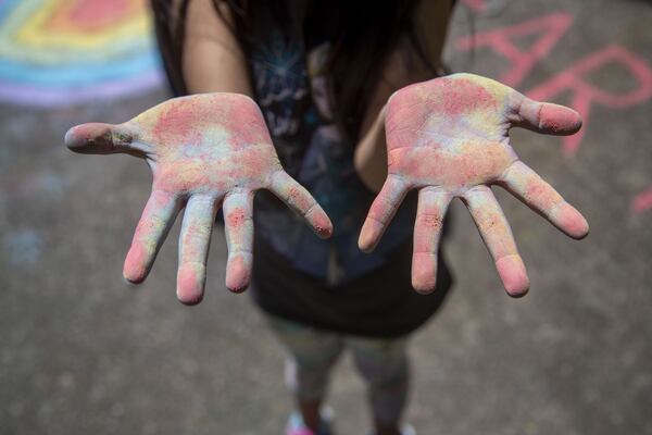 Berkeley Lake Elementary School first grader Milena Sanchez shows off her chalk dusted hands after helping Kathy Bentley create an encouraging message in Duluth on Friday, May 1, 2020. ALYSSA POINTER / ALYSSA.POINTER@AJC.COM