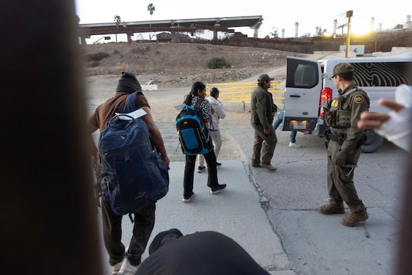 Migrants make their way to a Border Patrol van after crossing illegally and waiting to apply for asylum between two border walls separating Mexico and the United States, Tuesday, Jan. 21, 2025, in San Diego. (AP Photo/Gregory Bull)