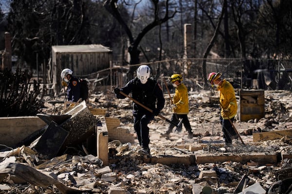 A search and rescue crew sifts through the wreckage of a home destroyed by the Eaton Fire, Tuesday, Jan. 14, 2025, in Altadena, Calif. (AP Photo/John Locher)