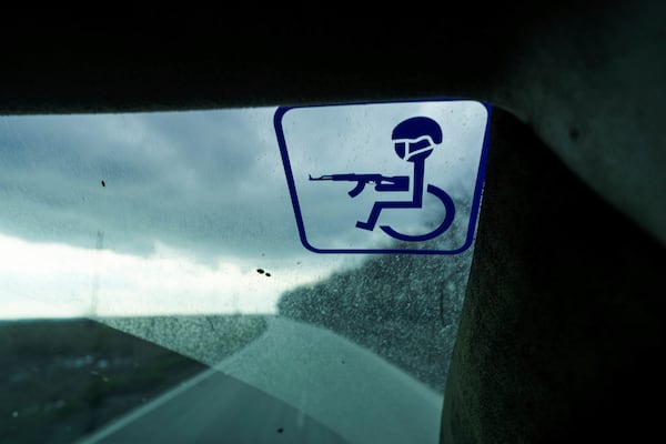 A sticker of a wheelchair-bound soldier holding a rifle is seen on the windshield of Oleksandr Puzikov, a captain with Ukraine's 127th brigade who lost an arm in combat, during a drive in Ukraine's Kharkiv region on Feb. 3, 2025. (AP Photo/Evgeniy Maloletka)