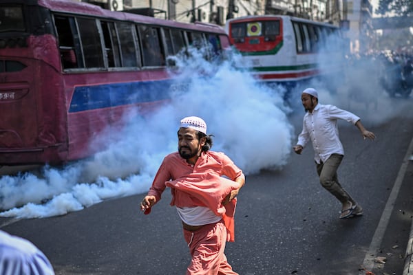 Members and supporters of the banned Islamist group Hizbut Tahrir run after police used teargas to disperse them near Baitul Mokarram Mosque in Dhaka, Bangladesh, Friday, March 7, 2025. (AP Photo/Mahmud Hossain Opu)