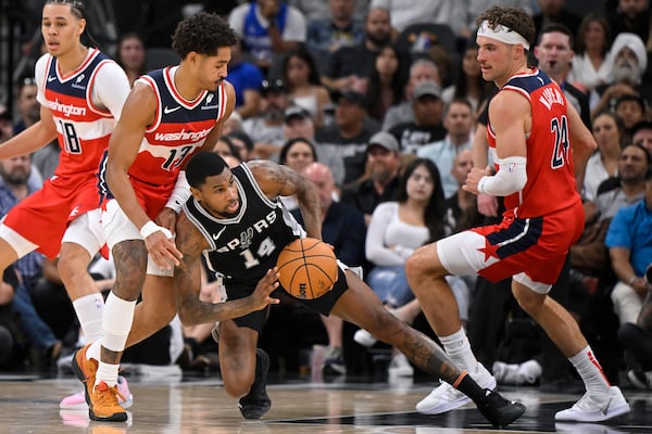 San Antonio Spurs' Blake Wesley (14) tangles with Washington Wizards' Jordan Poole (13) and Corey Kispert during the first half of an NBA basketball game, Thursday, Nov. 13, 2024, in San Antonio. (AP Photo/Darren Abate)