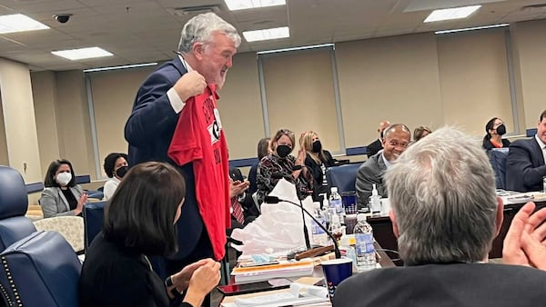 Georgia Board of Regents chair Harold Reynolds, a Georgia Tech graduate, holds up a Georgia Bulldogs T-shirt given to him by acting University System of Georgia Chancellor Teresa MacCartney during the Jan. 13, 2022, meeting. (Eric Stirgus/eric.stirgus@ajc.com)