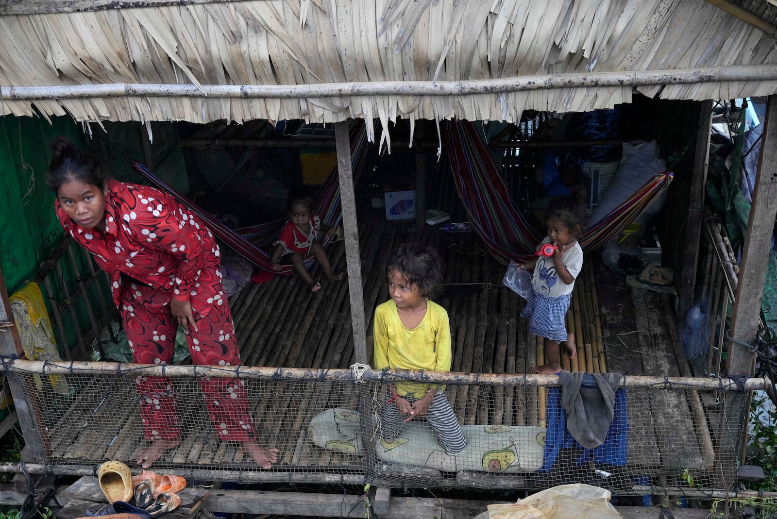 A fisher family in their home at a floating village, by the Tonle Sap in Kampong Chhnang province, Cambodia, Thursday, Aug. 1, 2024, (AP Photo/Heng Sinith)