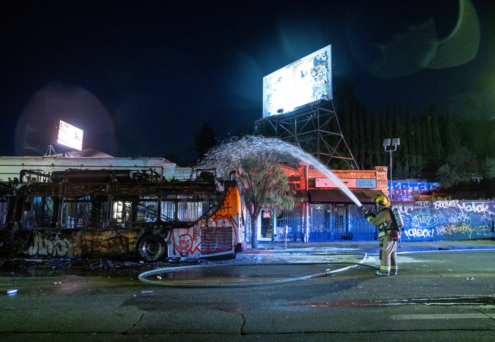 Firefighters douse water on a bus that was set on fire at Sunset and Echo Park after people gathered on the streets after the Los Angeles Dodgers defeated the New York Yankees to win the baseball World Series early Thursday, Oct. 31, 2024, in Los Angeles. (AP Photo/Ethan Swope)