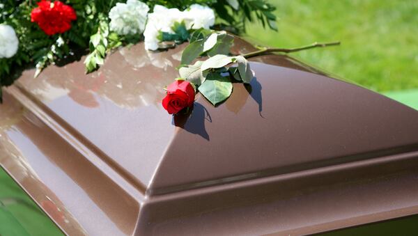 A single brown casket with a spray of flowers (stock photo).