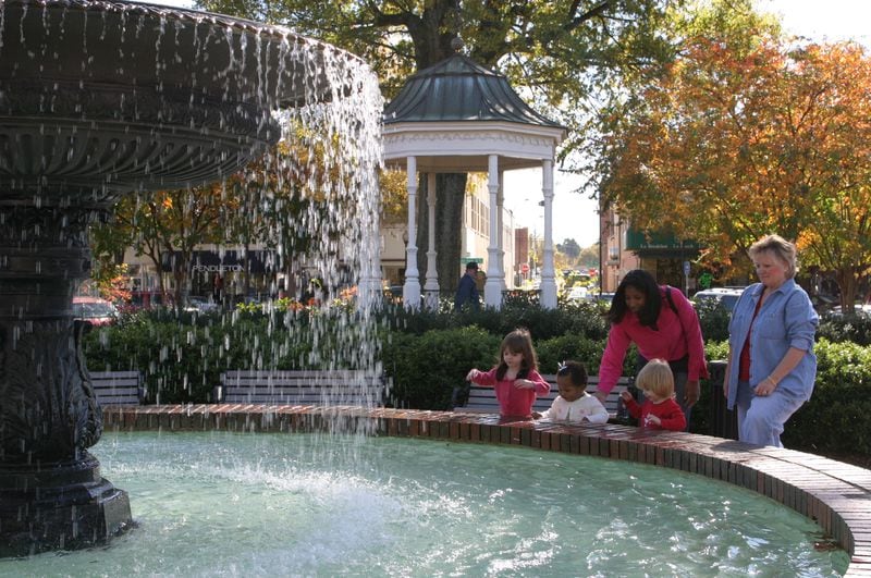 From the early 2000s: Michelle Marbury of Acworth, in the pink shirt, plays with her 1-year-old daughter Imani, in the white shirt, on the Square in Marietta. She is joined by Jean Autry and her two granddaughters, 3-year-old Isabella Bowling (left) and 2-year-old Julia Bowling (right).