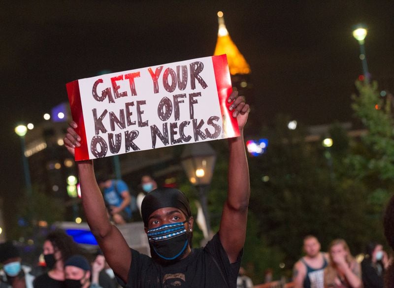 There have been protests in Atlanta in the wake of deaths of George Floyd and other African Americans. The sign held by this protester on May 29, 2020, is a reaction to the Minneapolis police officer who had his knee on Floyd’s neck before Floyd died. JENNI GIRTMAN FOR THE ATLANTA JOURNAL-CONSTITUTION
