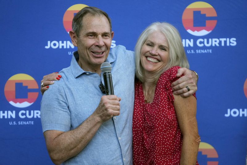 U.S. Rep. John Curtis hugs his wife Sue while addressing supporters after his win during an election night party, Tuesday, June 25, 2024, in Provo, Utah. Curtis has won the Utah GOP primary for Mitt Romney's open U.S. Senate seat, defeating one opponent who was endorsed by former President Donald Trump and others who said they supported Trump's agenda. (AP Photo/Rick Bowmer)