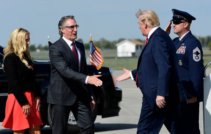 FILE - President Donald Trump reaches out to shake hands with North Dakota Gov. Doug Burgum, and his wife Kathryn Helgaas Burgum after arriving at Hector International Airport in Fargo, N.D., Sept. 7, 2018. (AP Photo/Susan Walsh, File)