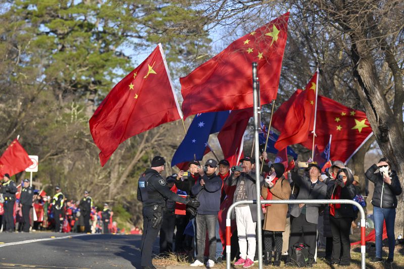 Supporters of Chinese Premier Li Qiang wait for his motorcade to pass outside Government House in Canberra, Monday, June 17, 2024. Li says he has agreed with Australian Prime Minister Anthony Albanese to properly manage their nations' differences as they emerge from a hostile era in which minister-to-minister contacts were banned and trade barriers cost Australian exporters up to $13 billion a year. (Mick Tsikas/Pool Photo via AP)