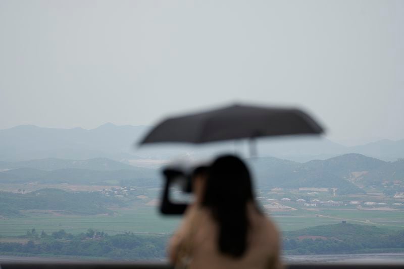 A visitor uses binoculars to see the North Korean side from the unification observatory in Paju, South Korea, Friday, June 21, 2024. On Friday, South Korea’s military said it had fired warnings shots the previous day to repel several North Korean soldiers who briefly crossed the military demarcation line that divides the countries while engaging in unspecified construction work. Because of an overgrowth of foliage, the North Koreans may not have seen the signs marking the thin military demarcation line that divides the DMZ into northern and southern sides since the 1950-53 Korean War. (AP Photo/Lee Jin-man)